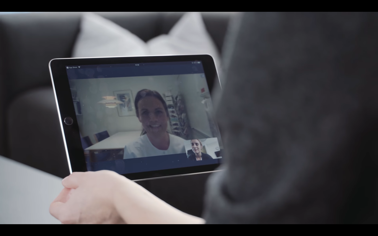 Patient siddende med IPad hvor på hun har konsultation med sygeplejerske