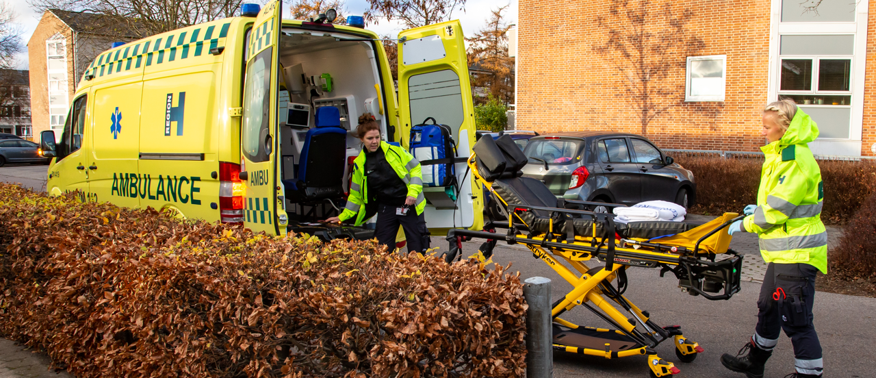 To ambulancereddere er ved at køre båre ind i bilen