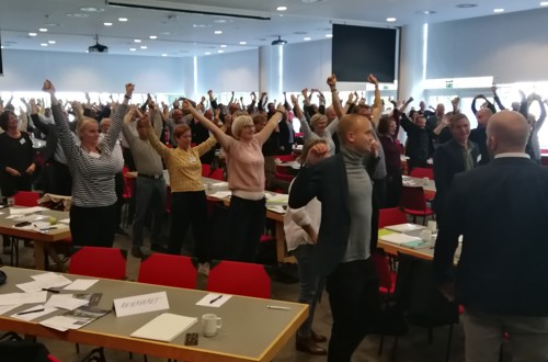 Forsamling af mennesker laver fysisk opvarmning i konferencelokale