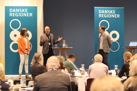 Formand for Danske Regioner Anders Kühnau (A) taler på scenen. Formand for sundhedsudvalget, Karin Friis Bach (B), til venstre og formand for udvalget for miljø og klima, Mads Duedahl (V), til højre